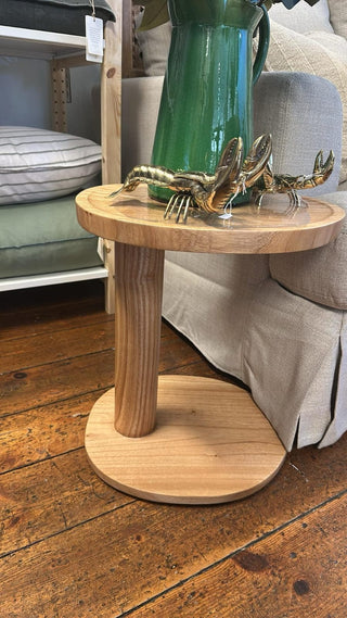 Wooden side table with a green vase and decorative crab on a wooden floor.
