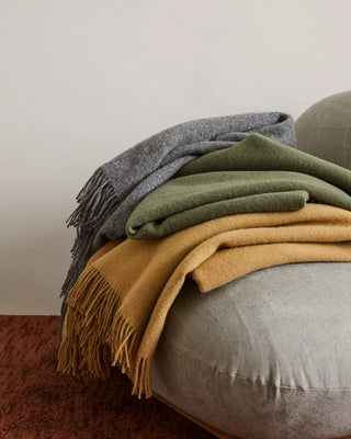 Stack of colorful blankets on a gray surface with a neutral background
