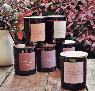 Collection of 'La Bella Luce' candles on a wooden surface with floral background