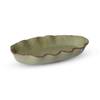 Green ceramic dish with wavy edge on a white background