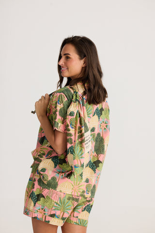 Woman wearing a tropical print dress on a white background
