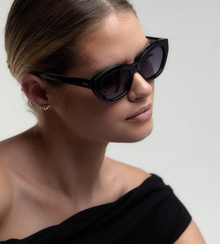 Woman wearing black sunglasses with a plain background