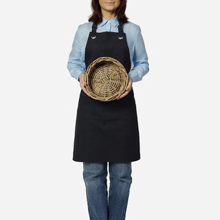 Person wearing a black apron holding a woven basket on a white background