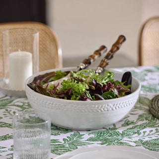 Bowl of salad on a table with a candle and glasses in the background