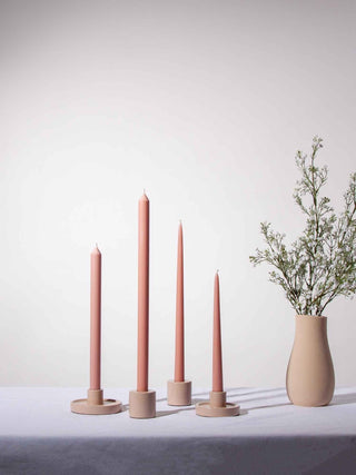 Set of pink candles in ceramic holders on a white surface with a light background