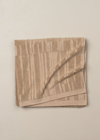 Folded beige towel on a light beige background