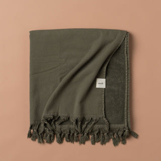 Green towel with tassels on a beige background