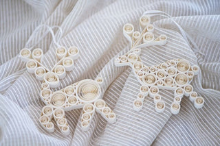 Two paper quilled deer ornaments on a textured white fabric background