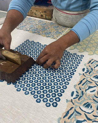 Person applying a blue pattern to fabric using a stamp tool.