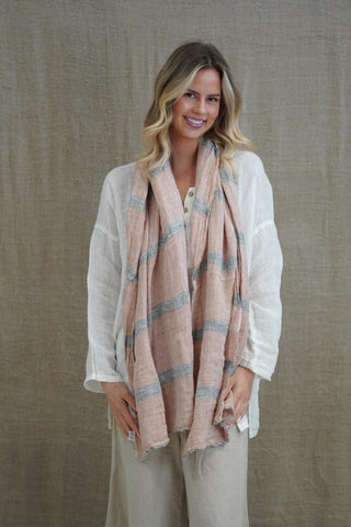 Woman wearing a beige scarf with a subtle pattern against a neutral background
