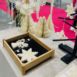 Decorative items including paper snowflakes and trees on a table with a pink carpet background.