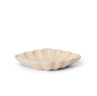 Beige ceramic dish with scalloped edge on a white background