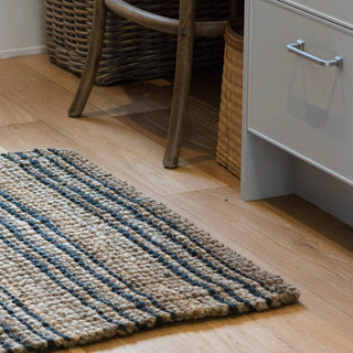 Textured rug with blue and beige stripes on a wooden floor.