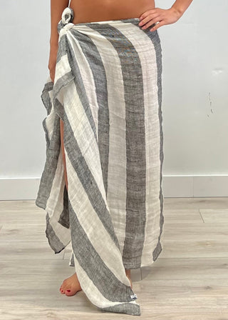 Person wearing a striped gray and white sarong on a wooden floor.