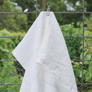 White towel hanging on a clothesline with a green outdoor background