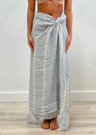 Person wearing a light blue and white striped sarong on a plain background