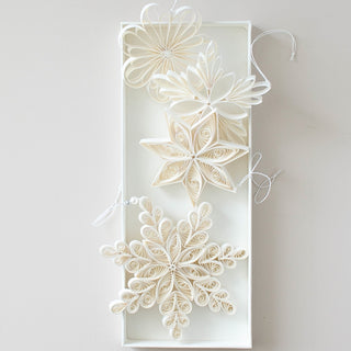 Decorative paper snowflakes in a white box on a light gray background