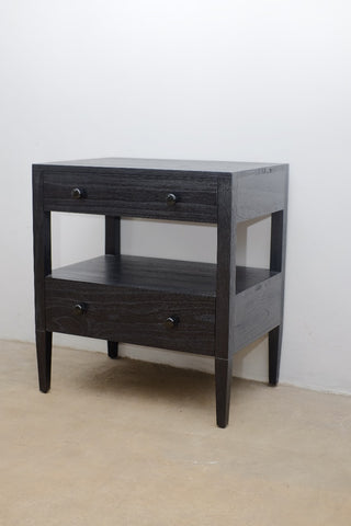 Dark wooden side table with two drawers on a beige floor and white wall background