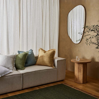 Living room with beige sofa, decorative pillows, wooden side table, and mirror.