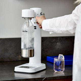 Person using a white aarke water bottle and dispenser on a kitchen counter.