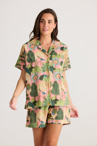 Woman wearing a colorful cactus patterned outfit on a plain background