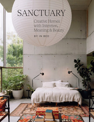 Modern bedroom with large white pendant light and 'Sanctuary' book title.