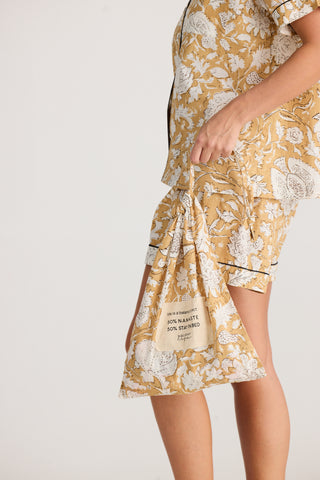 Person wearing a yellow and white floral pajama set on a plain background