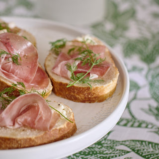 Bread slices with ham and herbs on a white plate