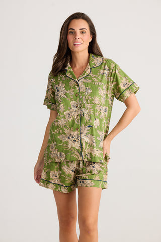 Woman wearing a green floral pajama set on a white background
