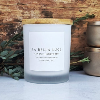 Frosted candle with wooden lid and 'La Bella Luce' label on a wooden background