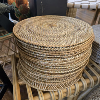 Stack of woven placemats on a wicker stool