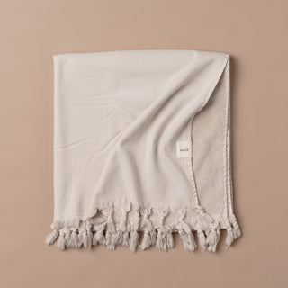 Beige towel with tassels on a beige background