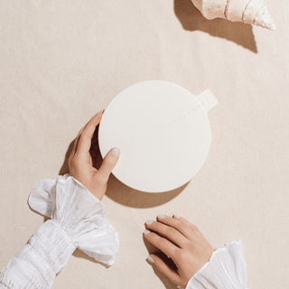 Person holding a white ceramic bowl on a beige surface
