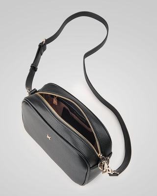 Black leather handbag with a gold zipper on a light gray background