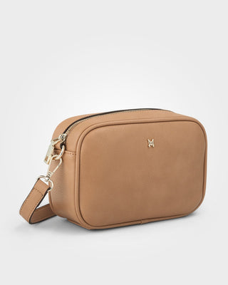 Tan crossbody bag with a visible brand logo on a light gray background