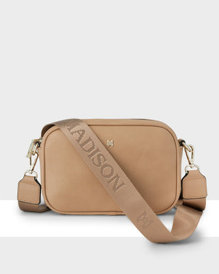 Tan handbag with visible brand name on a light gray background