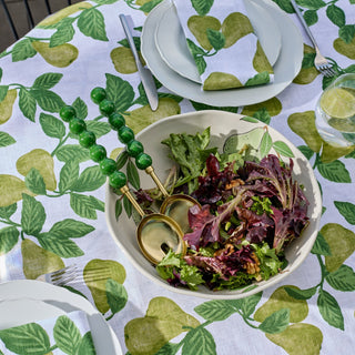 Table setting with a bowl of salad on a tablecloth with green leaf pattern