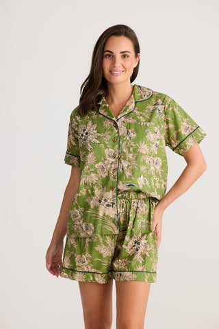 Woman wearing a green floral pajama set on a white background