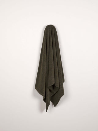 Dark green towel hanging on a white wall