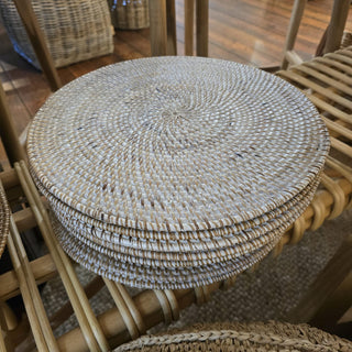 Stack of woven placemats on a wooden chair
