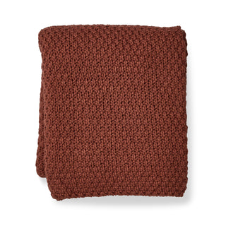 Folded brown knitted blanket on a white background