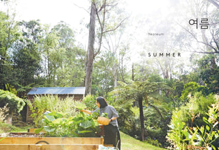 Person tending to plants in a garden with a cabin in the background, labeled 'Summer'.