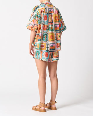 Person wearing a colorful patterned shirt and shorts on a white background