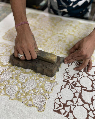 Person using a wooden block to print intricate patterns on fabric.