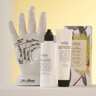 Salus hand care products including a ceramic hand model, bottles, and a tube on a light background