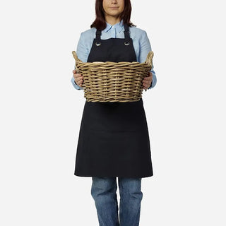 Person wearing a black apron holding a woven basket on a white background