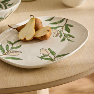 Decorative plate with pears and floral designs on a wooden table
