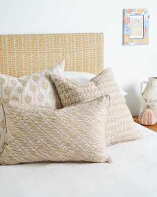 Bed with patterned pillows and a decorative headboard in a bedroom setting.