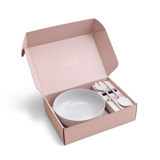 Pink gift box with a white bowl and cutlery set on a white background