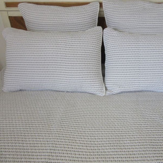 Four textured pillows on a sofa with a neutral background
